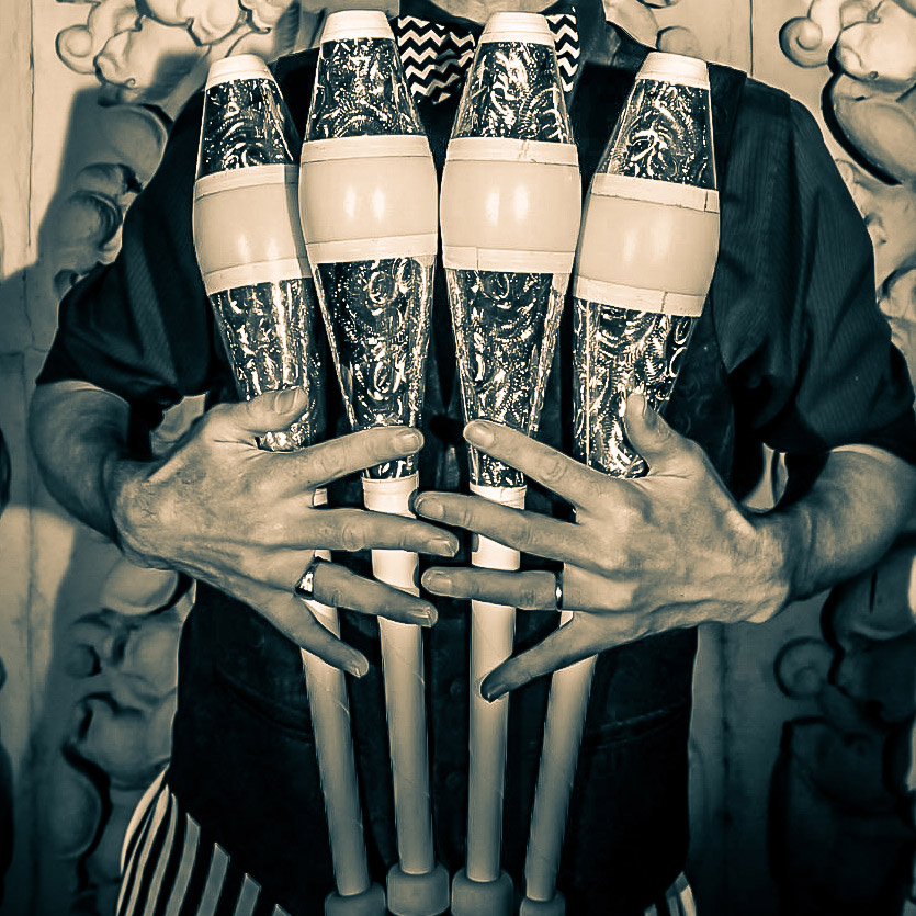 Man Holding Four Juggling Clubs
